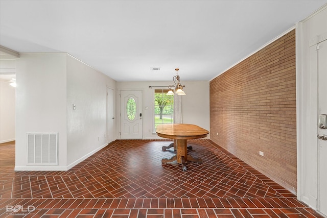entrance foyer featuring baseboards, brick patterned floor, brick wall, and visible vents