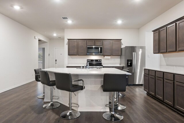 kitchen featuring dark brown cabinets, stainless steel appliances, dark wood-type flooring, and visible vents
