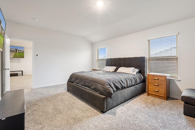 bedroom featuring light colored carpet, baseboards, and lofted ceiling