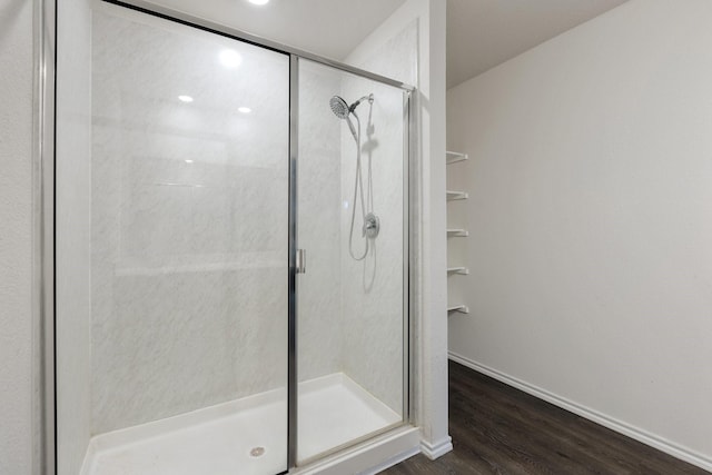 full bathroom featuring a shower stall, baseboards, and wood finished floors