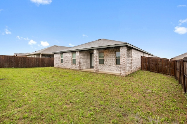 rear view of property with a yard, a patio, brick siding, and a fenced backyard