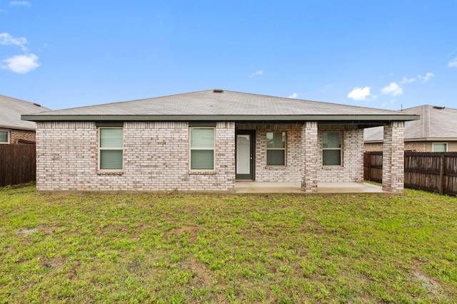 rear view of house featuring a yard, a patio, brick siding, and a fenced backyard