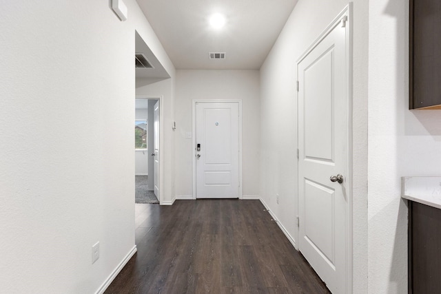 hallway featuring dark wood finished floors, visible vents, and baseboards
