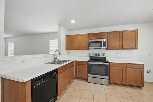 3105 Lipizzan Dr, Denton, TX 76210 - kitchen with appliances with stainless steel finishes, a sink, brown cabinets, light countertops, and a peninsula