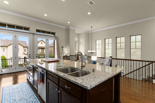 kitchen with a sink, a kitchen island with sink, visible vents, dark wood finished floors, and a notable chandelier