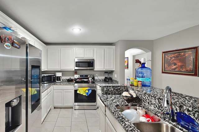 600 Saint Luke St, Terrell, TX 75160 - kitchen with light tile patterned floors, a sink, white cabinetry, arched walkways, and appliances with stainless steel finishes