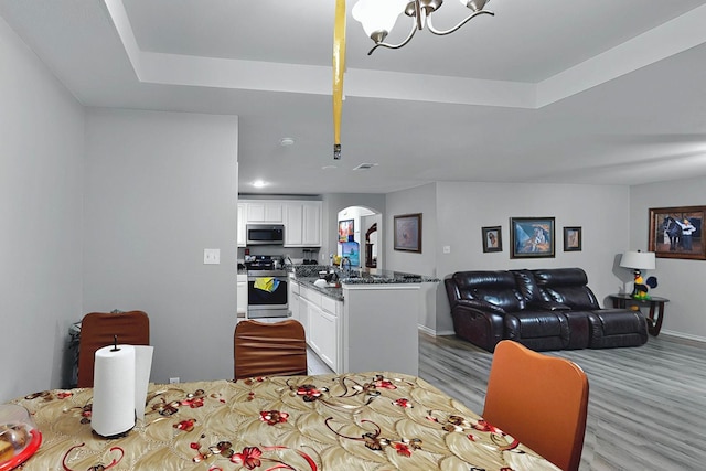 600 Saint Luke St, Terrell, TX 75160 - dining room featuring visible vents, light wood-style flooring, arched walkways, a notable chandelier, and baseboards
