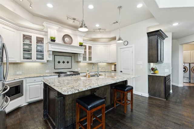 500 Denton Creek Dr, Mckinney, TX 75072 - kitchen featuring a sink, stainless steel microwave, washing machine and clothes dryer, white cabinets, and a breakfast bar area