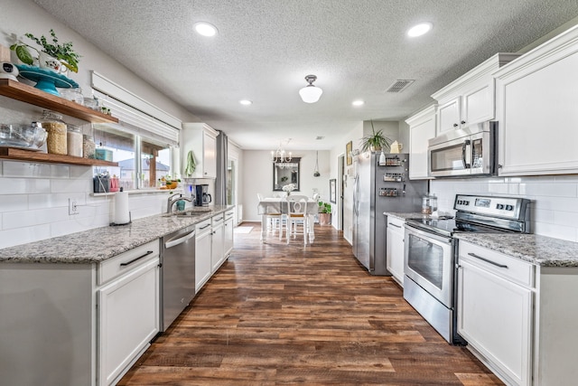 kitchen featuring dark wood-style flooring, visible vents, a sink, tasteful backsplash, and appliances with stainless steel finishes