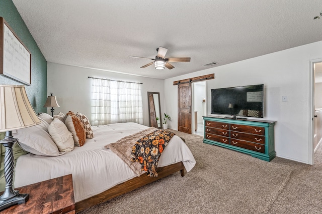 bedroom with carpet, a textured ceiling, visible vents, and a barn door