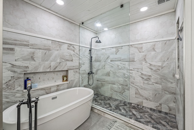 full bath with tile walls, recessed lighting, walk in shower, visible vents, and a soaking tub