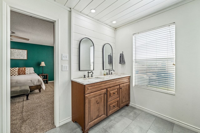ensuite bathroom with baseboards, ensuite bath, double vanity, and a sink