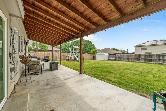 view of patio / terrace with a fenced backyard, an outdoor structure, a playground, and a storage unit