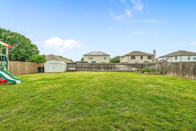 view of yard with a fenced backyard, a storage shed, a playground, and an outdoor structure