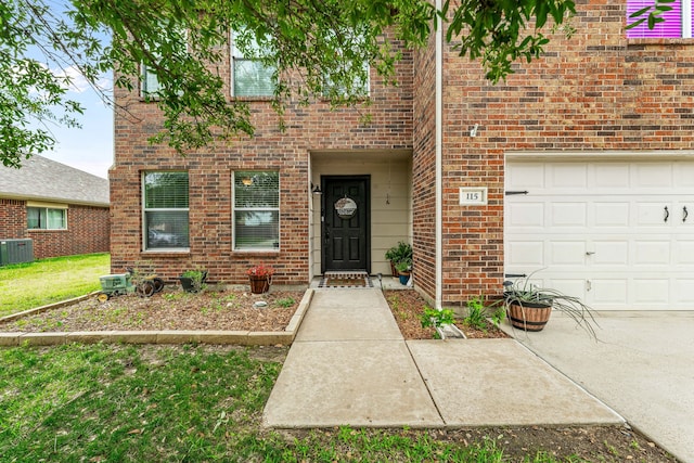 entrance to property with brick siding, central AC unit, and a garage