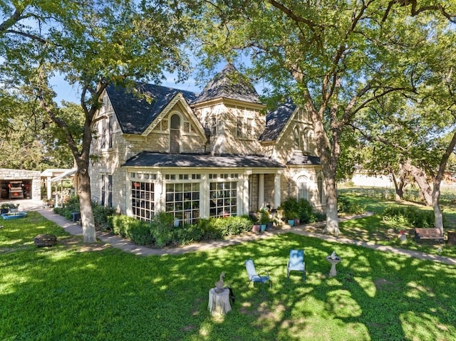rear view of house featuring stone siding and a yard