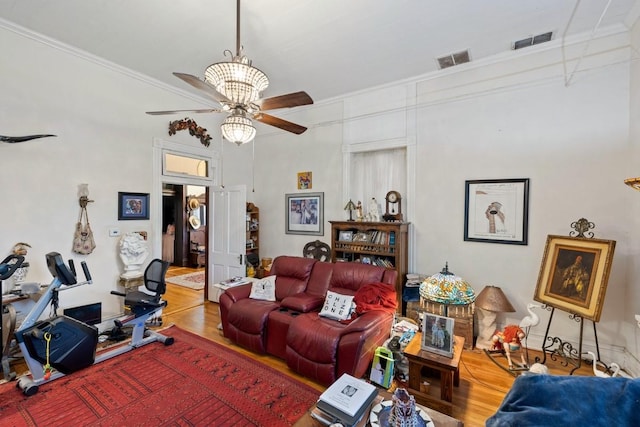 living room with ceiling fan, ornamental molding, visible vents, and wood finished floors