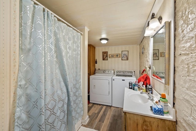 bathroom with wood finished floors, vanity, ornamental molding, washing machine and clothes dryer, and wallpapered walls