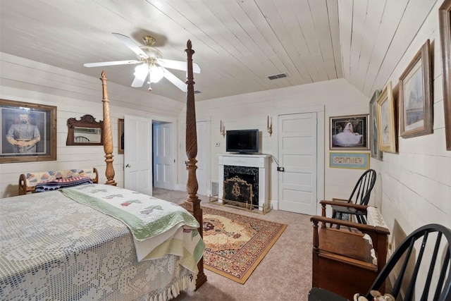 carpeted bedroom with a fireplace, vaulted ceiling, ceiling fan, and visible vents