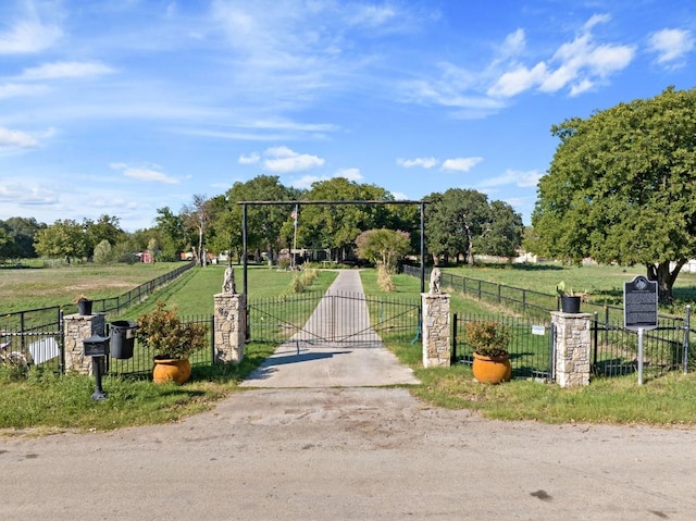 view of home's community with driveway, a gate, fence, and a lawn