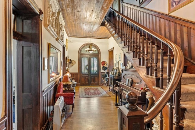 entrance foyer featuring a notable chandelier, stairway, wainscoting, and wood-type flooring