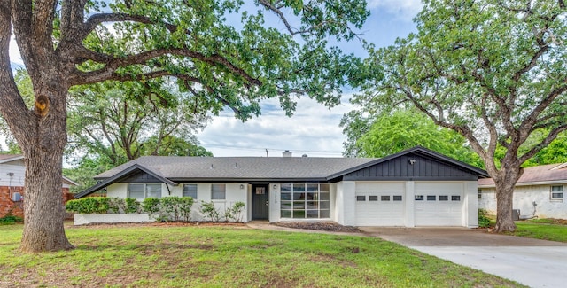 single story home with driveway, a garage, a front lawn, and board and batten siding