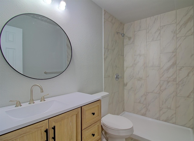 full bath featuring toilet, a tile shower, vanity, and a textured wall