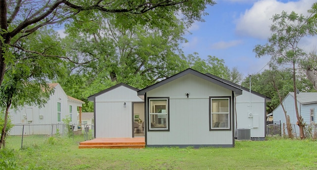 back of house with a wooden deck, a lawn, a fenced backyard, and central AC