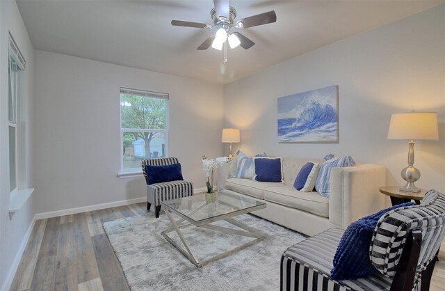 living room featuring wood finished floors, baseboards, and ceiling fan