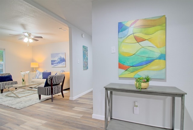 hall with baseboards, visible vents, and wood finished floors