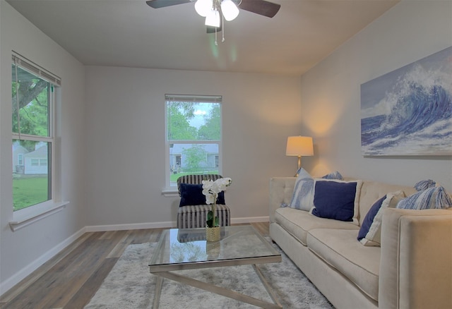 living area with baseboards, a ceiling fan, and wood finished floors