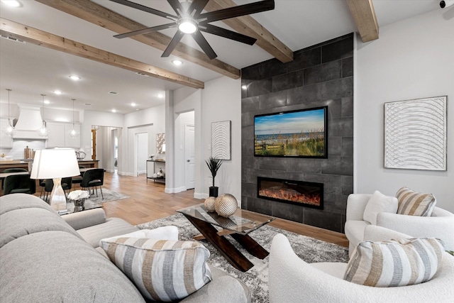 913 Beall St, Denton, TX 76207 - living room with light wood-style flooring, recessed lighting, a tiled fireplace, ceiling fan, and beamed ceiling