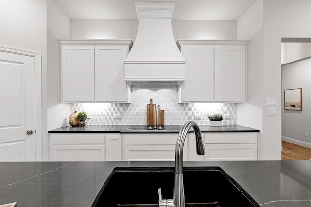 913 Beall St, Denton, TX 76207 - kitchen with white cabinetry, dark countertops, premium range hood, and a sink