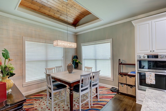 dining area featuring a tray ceiling, crown molding, dark wood-style flooring, baseboards, and a chandelier