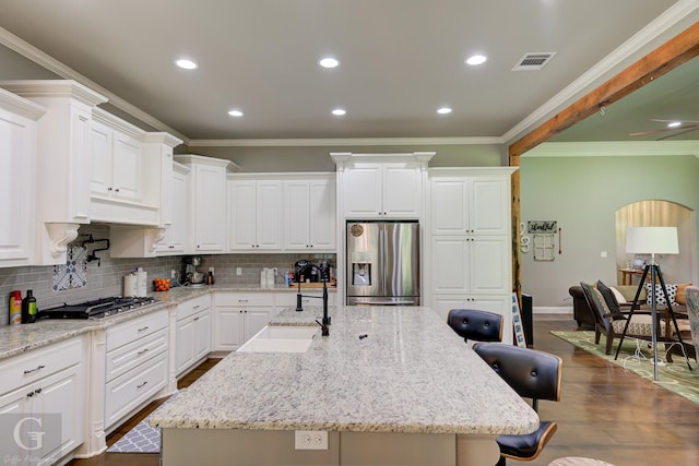 kitchen with a sink, ornamental molding, decorative backsplash, a kitchen bar, and appliances with stainless steel finishes