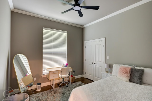 bedroom with a closet, wood finished floors, crown molding, ceiling fan, and baseboards