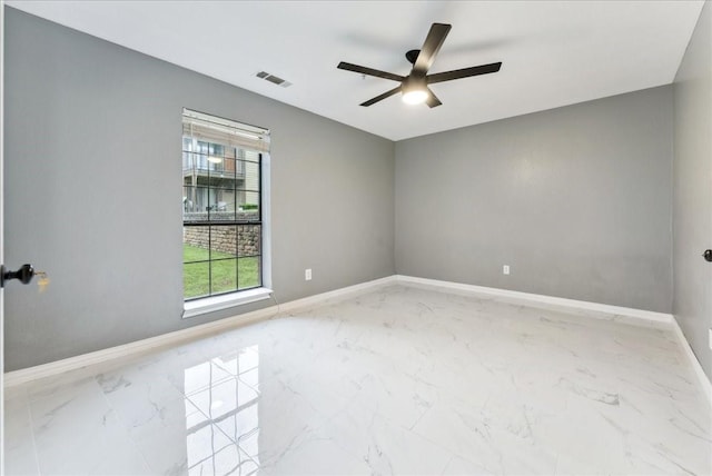 empty room with visible vents, marble finish floor, baseboards, and ceiling fan