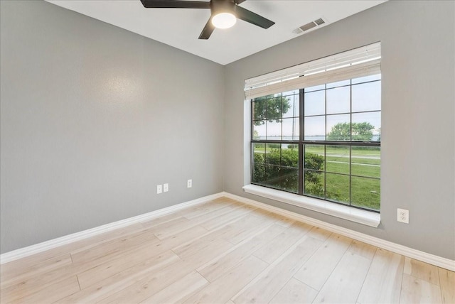 spare room featuring a ceiling fan, baseboards, light wood-type flooring, and visible vents