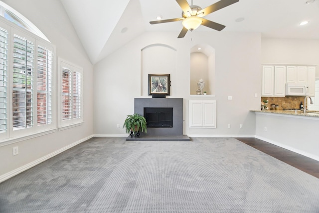 4118 Armistice Dr, Frisco, TX 75034 - unfurnished living room featuring baseboards, a glass covered fireplace, ceiling fan, a sink, and vaulted ceiling