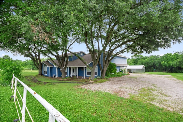 view of front facade with covered porch, a front lawn, and fence
