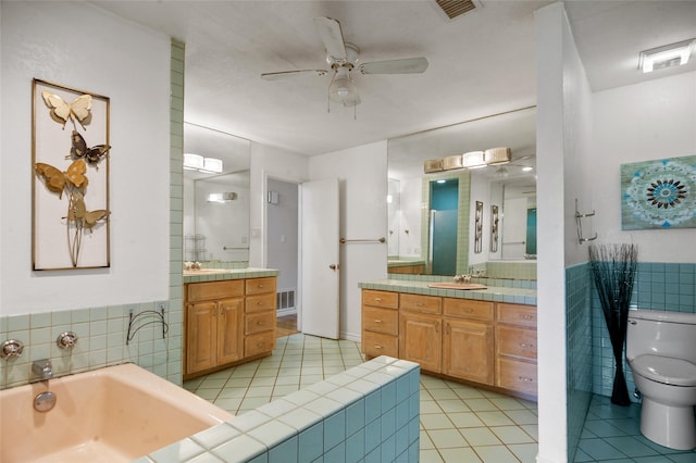 full bathroom featuring tile walls, toilet, ceiling fan, visible vents, and tile patterned floors