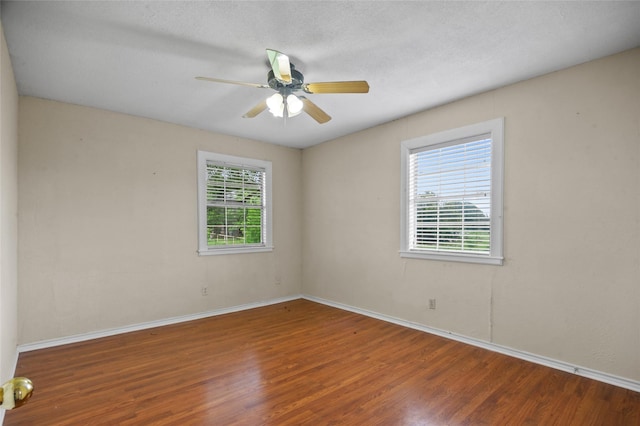unfurnished room with a ceiling fan, wood finished floors, and baseboards