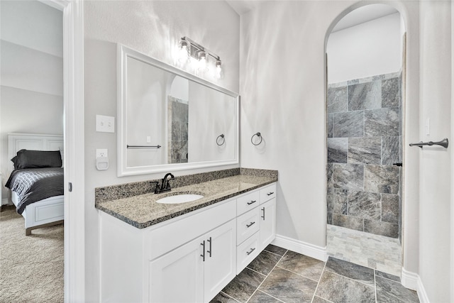 bathroom featuring baseboards, ensuite bathroom, vanity, and a walk in shower