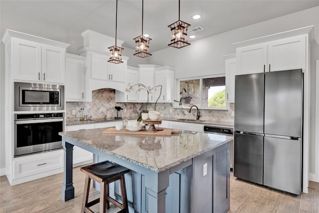 kitchen with a sink, stainless steel appliances, white cabinetry, and visible vents