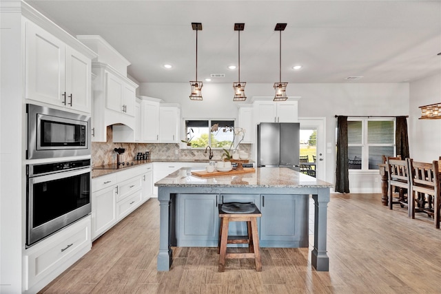 kitchen featuring a sink, a healthy amount of sunlight, white cabinetry, decorative backsplash, and appliances with stainless steel finishes
