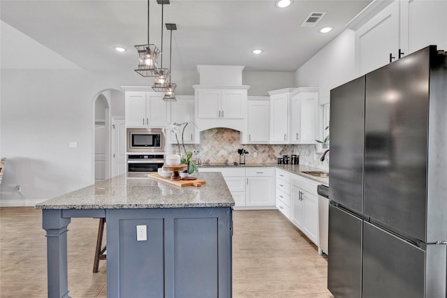 kitchen featuring white cabinets, stainless steel appliances, light wood finished floors, and visible vents