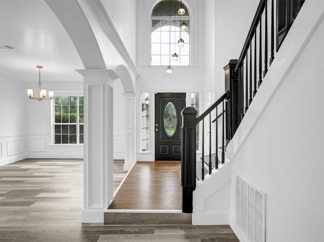 entrance foyer featuring a chandelier, visible vents, wood finished floors, and stairway