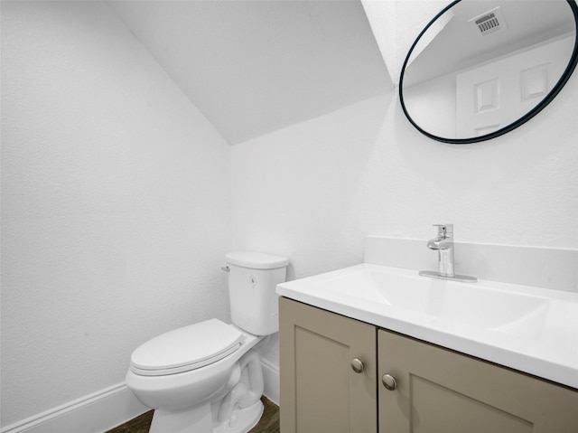 bathroom with toilet, vaulted ceiling, vanity, and visible vents