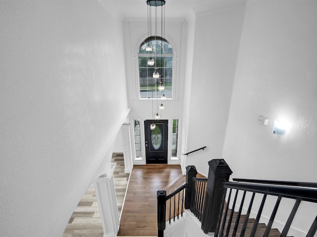 entrance foyer featuring stairway, a chandelier, crown molding, and wood finished floors