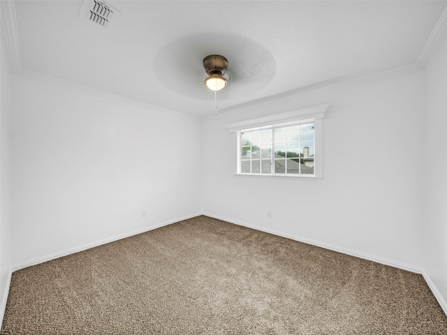 carpeted spare room with visible vents, baseboards, a ceiling fan, and ornamental molding